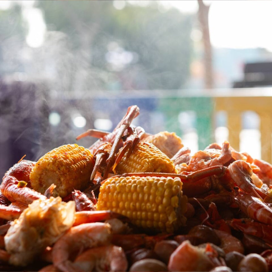 Boiled crawfish and corn on a table with a blurred outdoor background