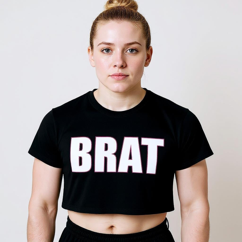Person wearing a black t-shirt with 'BRAT' text on a plain background
