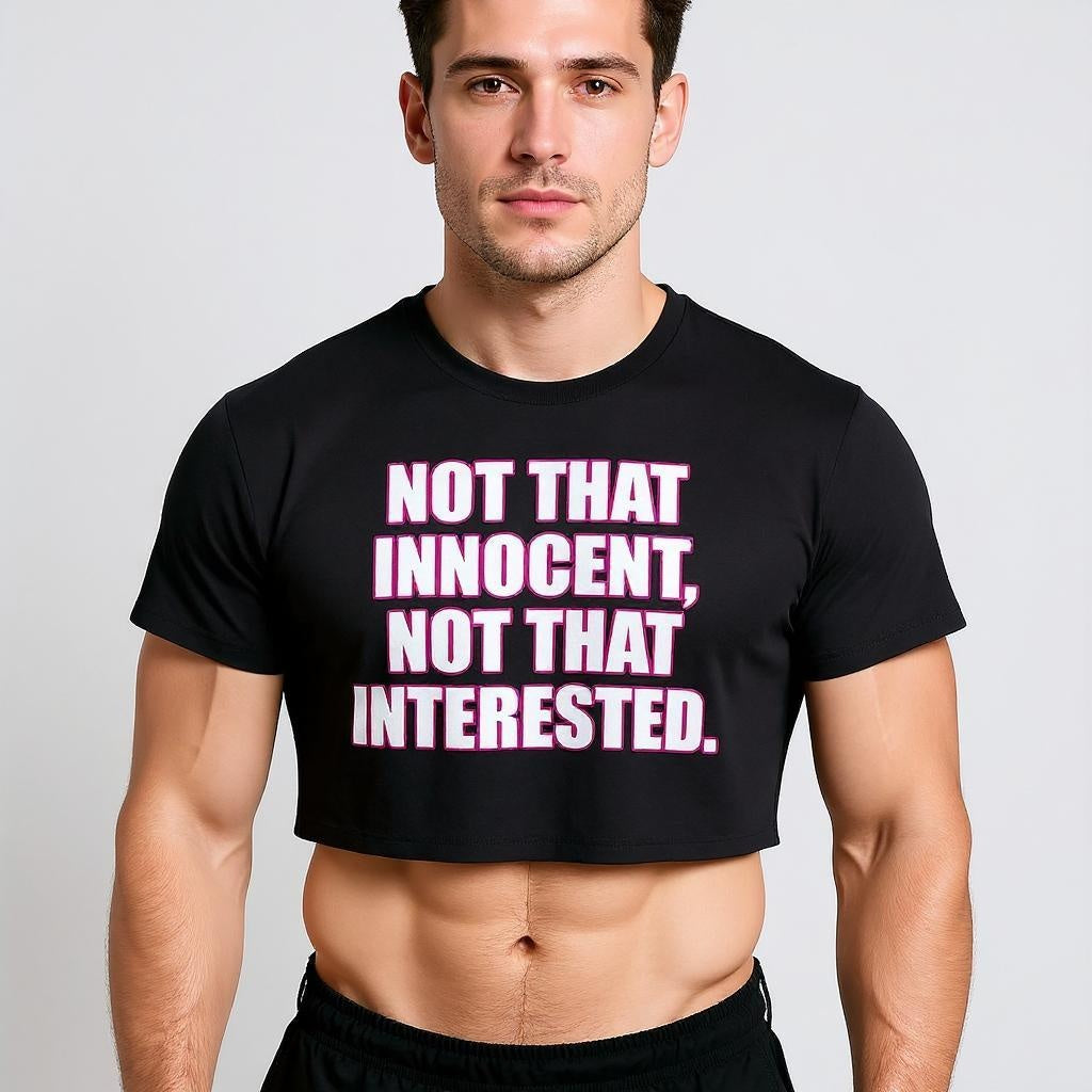 A cute boy wearing a black Britney t-shirt with pink text on a plain background that says, "Not that innocent, not that interested."