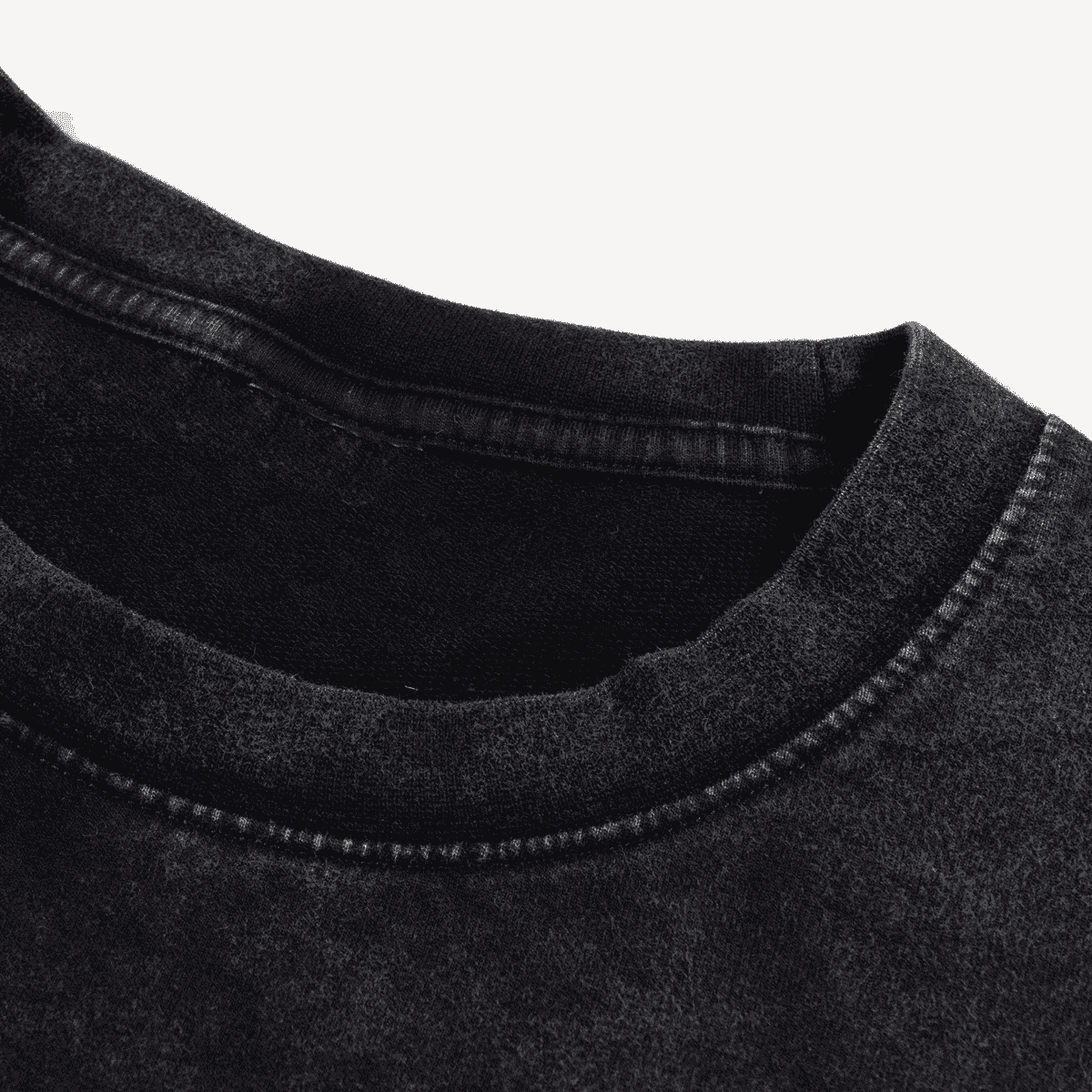 Close-up of a black denim fabric with stitching detail on a white background