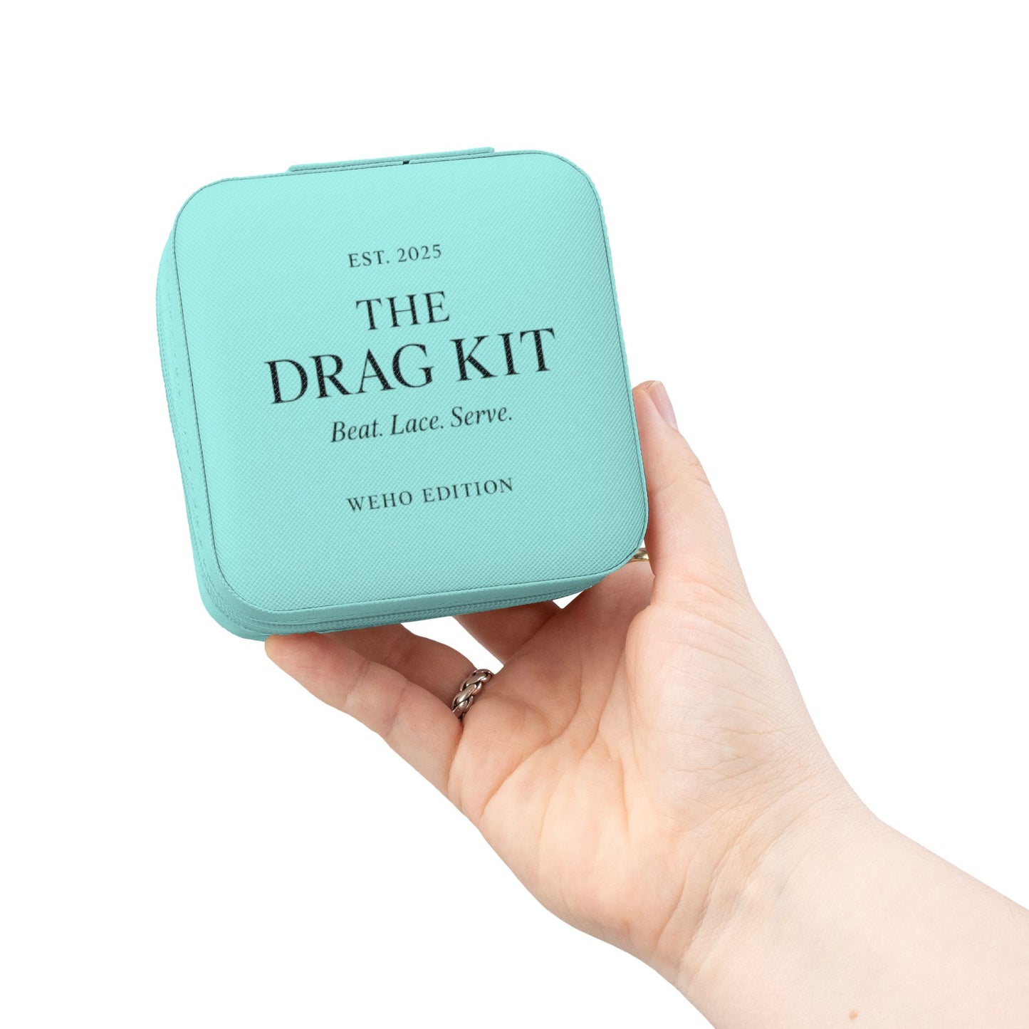 Hand holding a turquoise Tiffany blue colored box labeled 'The Drag Kit' on a white background
