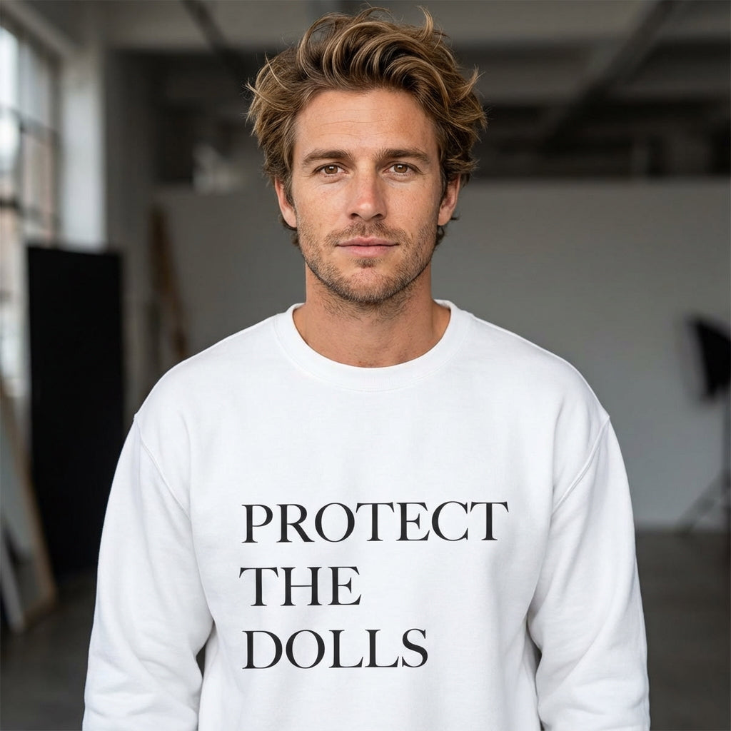 Man wearing a white sweatshirt with 'PROTECT THE DOLLS' text in a studio setting