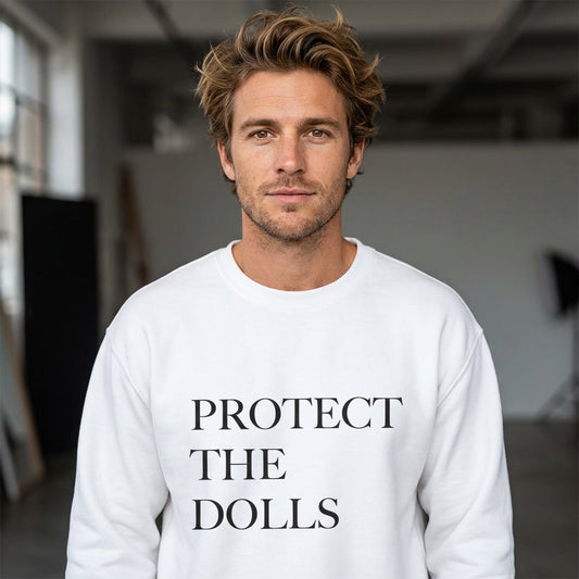 Man wearing a white sweatshirt with 'PROTECT THE DOLLS' text in a studio setting