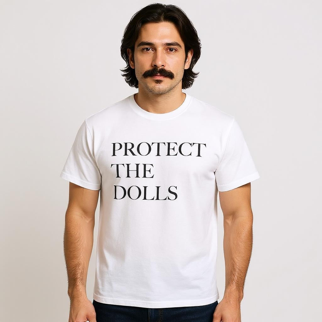 The model is wearing a white t-shirt with bold black text that reads “PROTECT THE DOLLS,” supporting trans rights, queer visibility, and inclusive LGBTQ+ streetwear fashion.