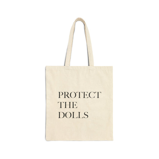 Beige tote bag with 'PROTECT THE DOLLS' text on a white background