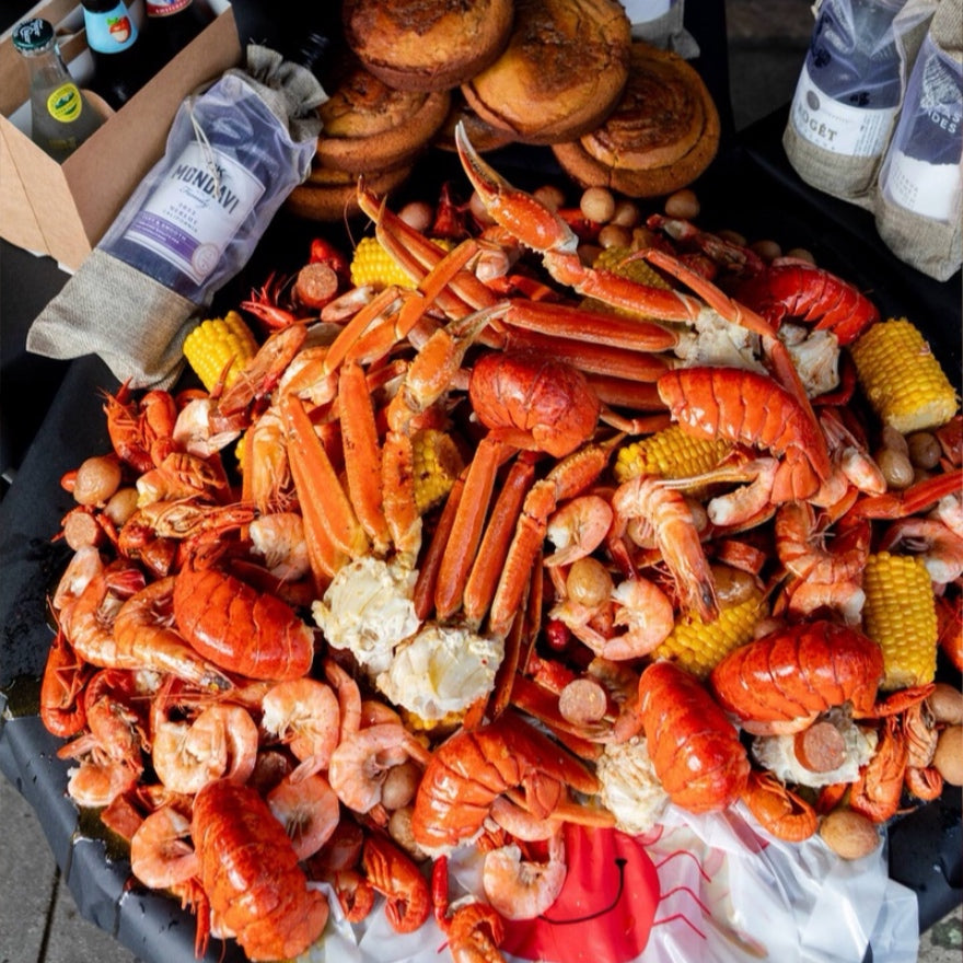 Assorted seafood, including lobsters and shrimp with corn, on a table owned and operated by LGBT people.