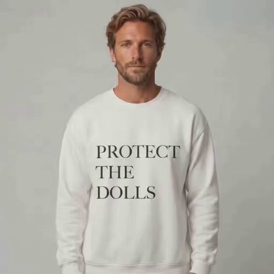 Protect the Dolls crewneck donation: a man wearing the trending crewneck with the words "Protect The Dolls" in black writing on the front of a white crewneck sweatshirt.