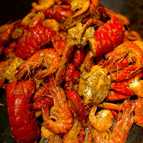 Seafood boil with shrimp, lobster tails, snow crab, and Cajun sides, made to share at a queer-owned West Hollywood restaurant.